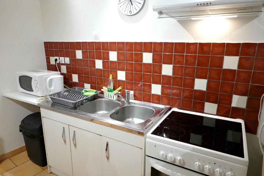 a kitchen with a sink and a microwave at Appart' de la collégiale in Bourbon-Lancy