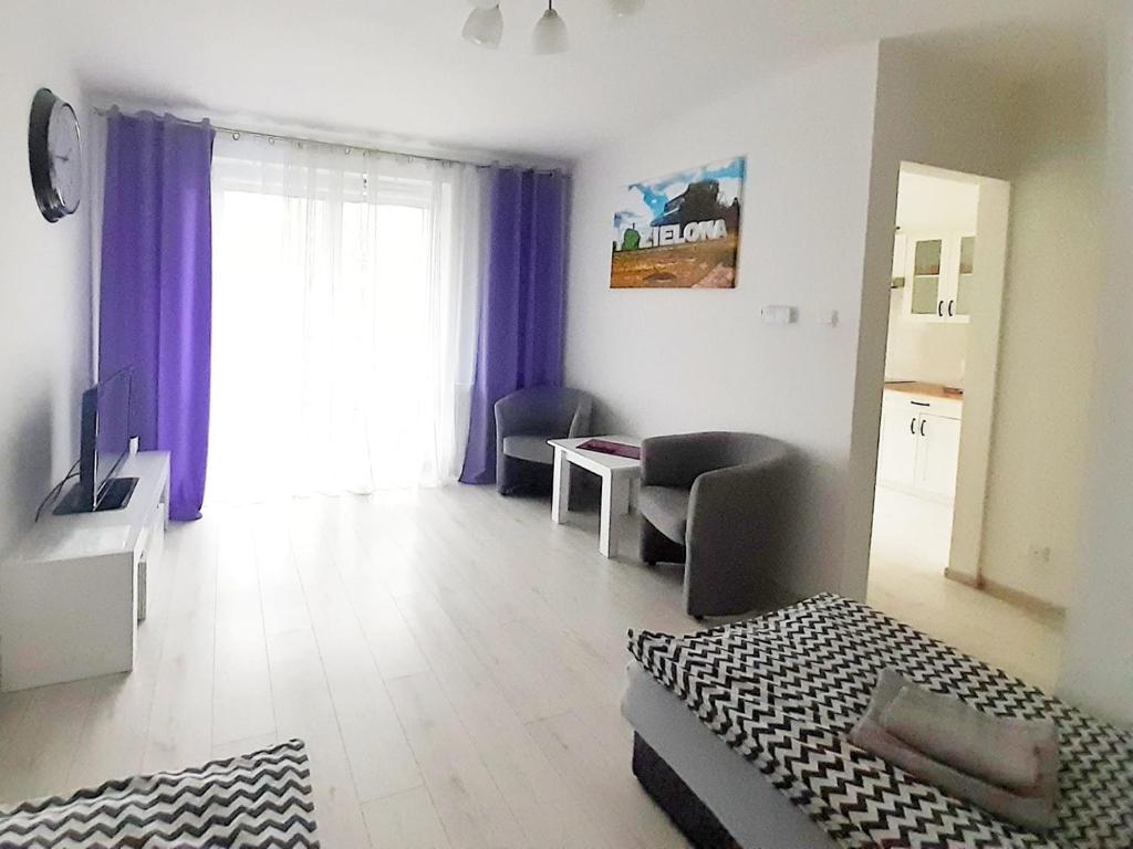 a room with a bed and a living room with a window at Apartament Złota Łącza in Zielona Góra