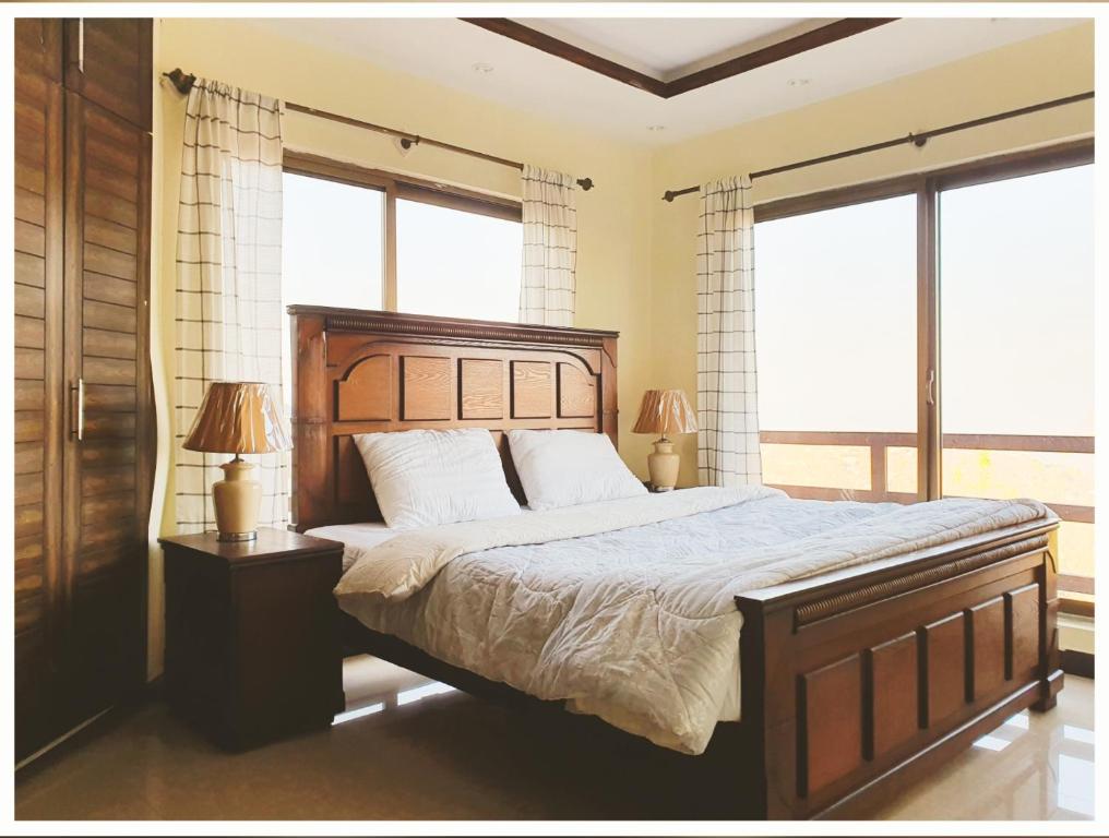 a bedroom with a large bed and two windows at Full Serviced Cottage in Bhurban in Ausia