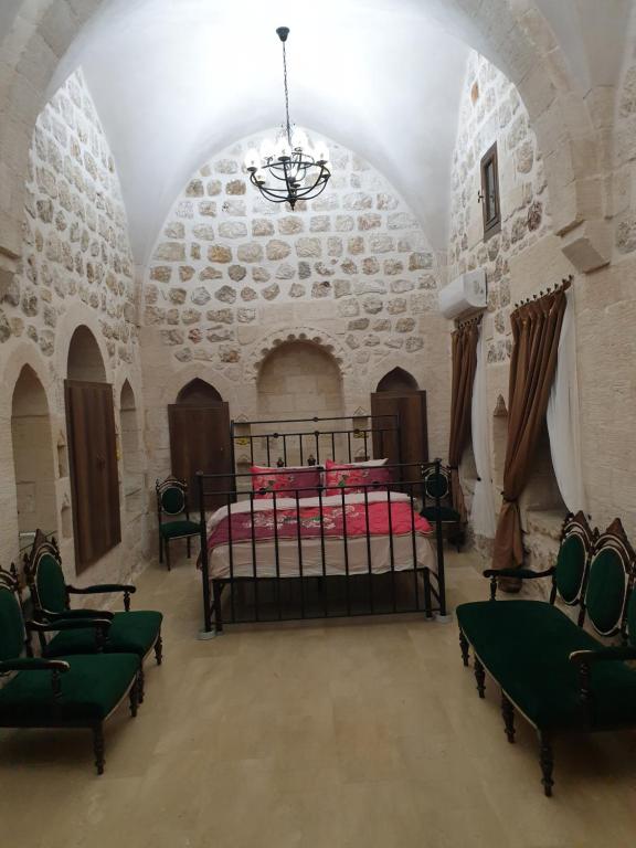 Mardin tarihi ulu Cami yanı, tarihi Konak في ماردين: غرفة نوم بسرير وكراسي في غرفة