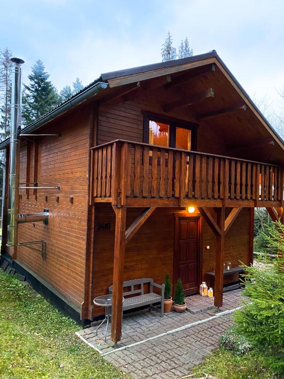 a large wooden cabin with a large deck at Chata TRI GROŠE 3 in Námestovo
