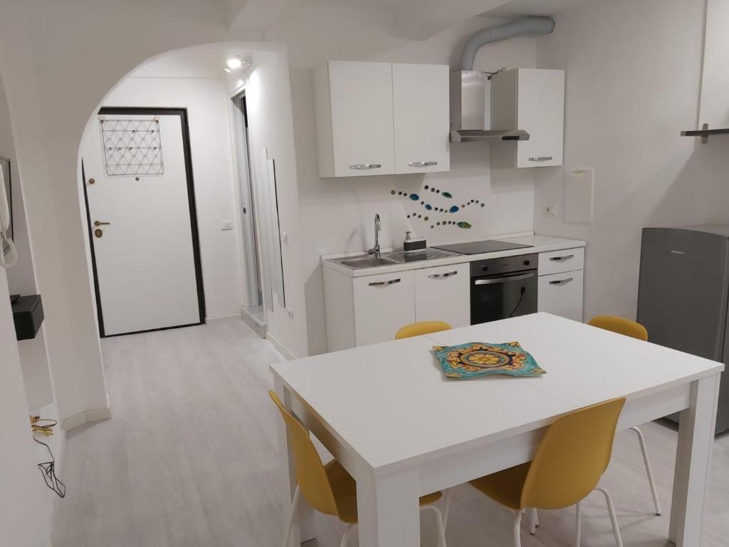 a white kitchen with a white table and chairs at HOLIDAY HOUSE FIERAVECCHIA in Salerno