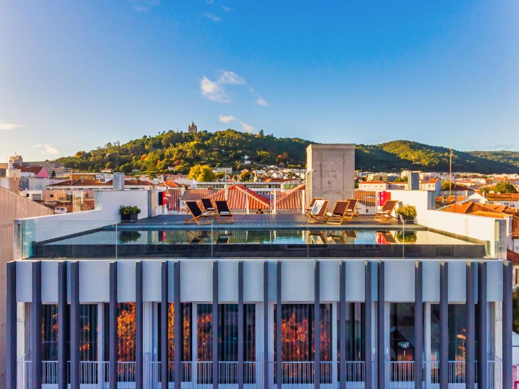 a building with a swimming pool on top of a city at Flag Design Hotel in Viana do Castelo