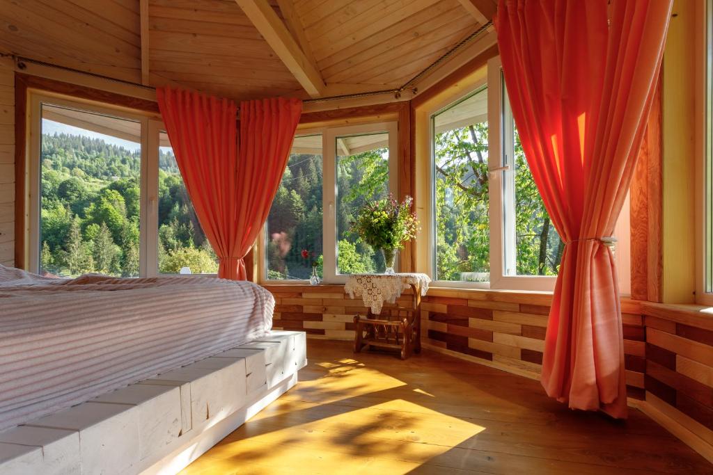 een slaapkamer met ramen en een bed en een stoel bij Хата Різьбяра - Закуток in Beloberëzka