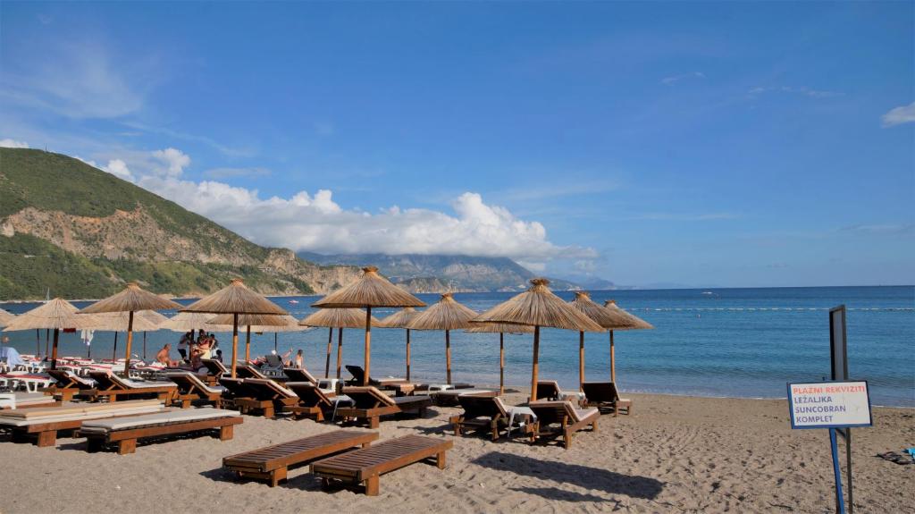 una playa con sillas y sombrillas y el océano en MM Apartments en Budva