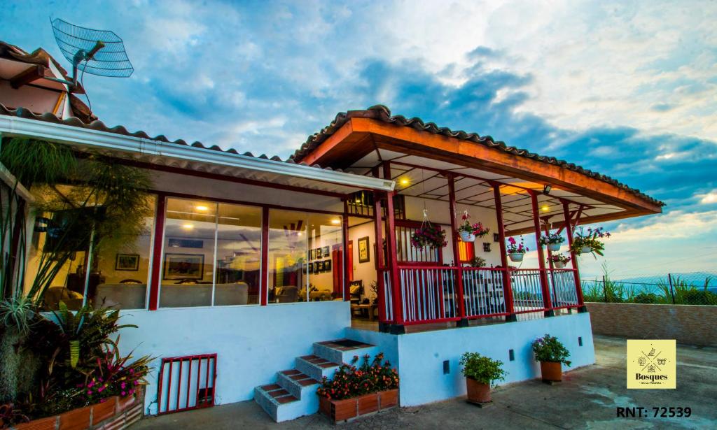 een klein huis met een veranda en een balkon bij Bosques de la Pradera in Manizales