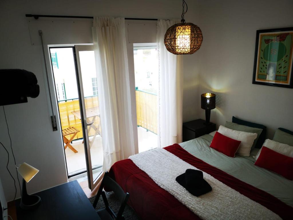 Schlafzimmer mit einem Bett mit roten Kissen und einem Fenster in der Unterkunft Peniche Surf Lodge 2 in Peniche