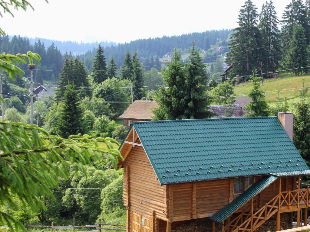 een houten hut met een blauw dak in een bos bij "Лісова Ягода" in Yablunytsia