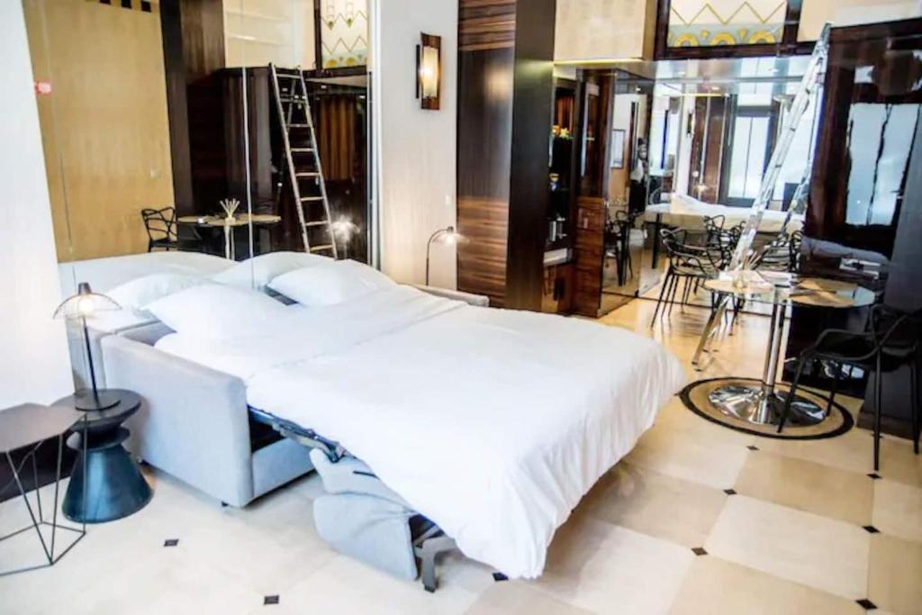 a bedroom with a large white bed and tables and chairs at Studio boisé à 2 pas du jardin du Luxembourg in Paris
