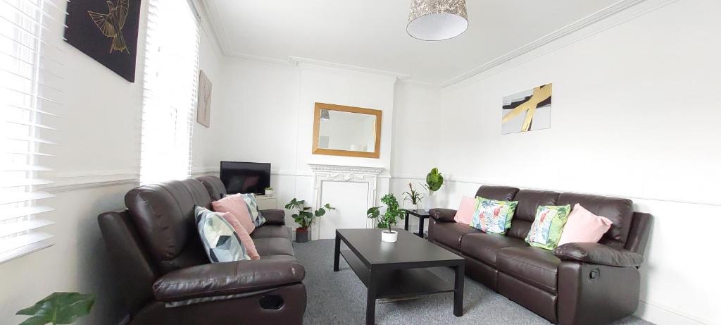 a living room with two leather couches and a table at Very spacious two bedroom converted apartment in East Croydon in Croydon