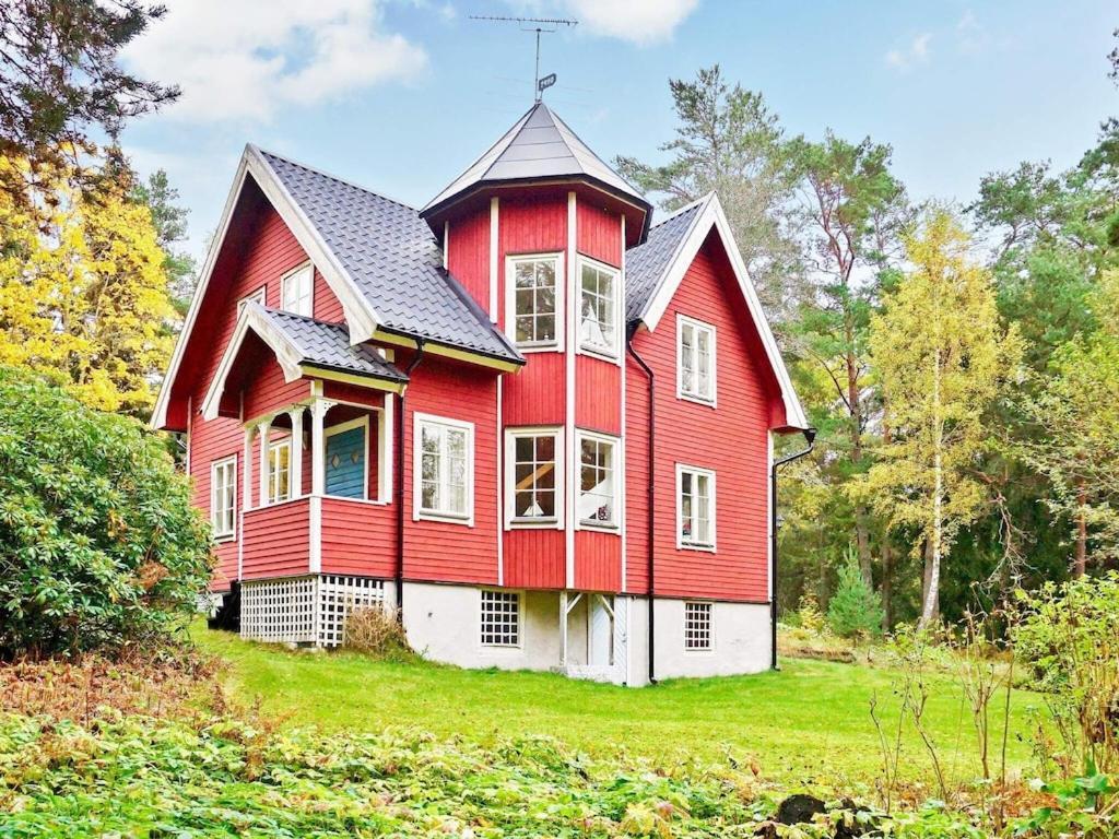 a red house with a black roof on a green field at 5 person holiday home in NORRT LJE in Nävekvarn