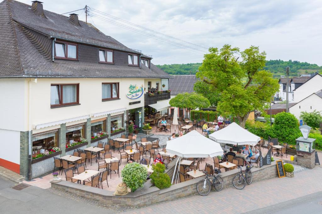 uitzicht op een restaurant met tafels en stoelen bij Eifel Hotel Schneider am Maar GmbH in Schalkenmehren