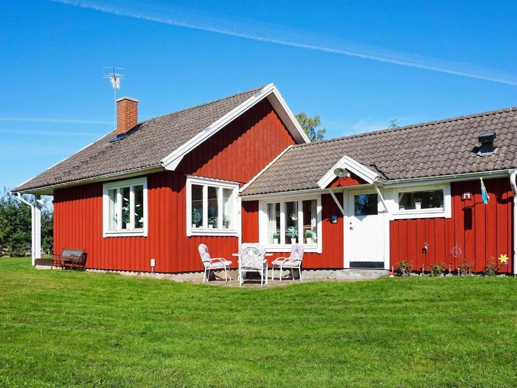 een rood huis met twee stoelen en een tafel bij 5 person holiday home in F RJESTADEN in Färjestaden