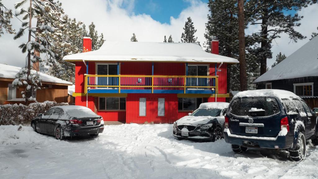 dos autos estacionados en la nieve frente a una casa en Tao Cabins en Big Bear City