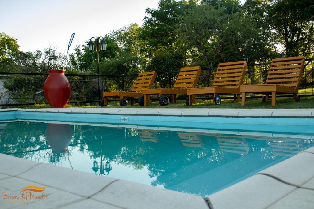 two chairs and a vase sitting next to a swimming pool at Cabañas Brisas Del Mirador in Bialet Massé