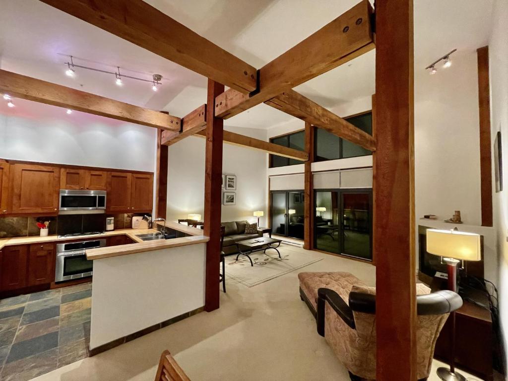 a kitchen with wooden beams and a living room at Luxurious Top Floor Villa With Sweeping Pacific Ocean - Bbv in Ucluelet