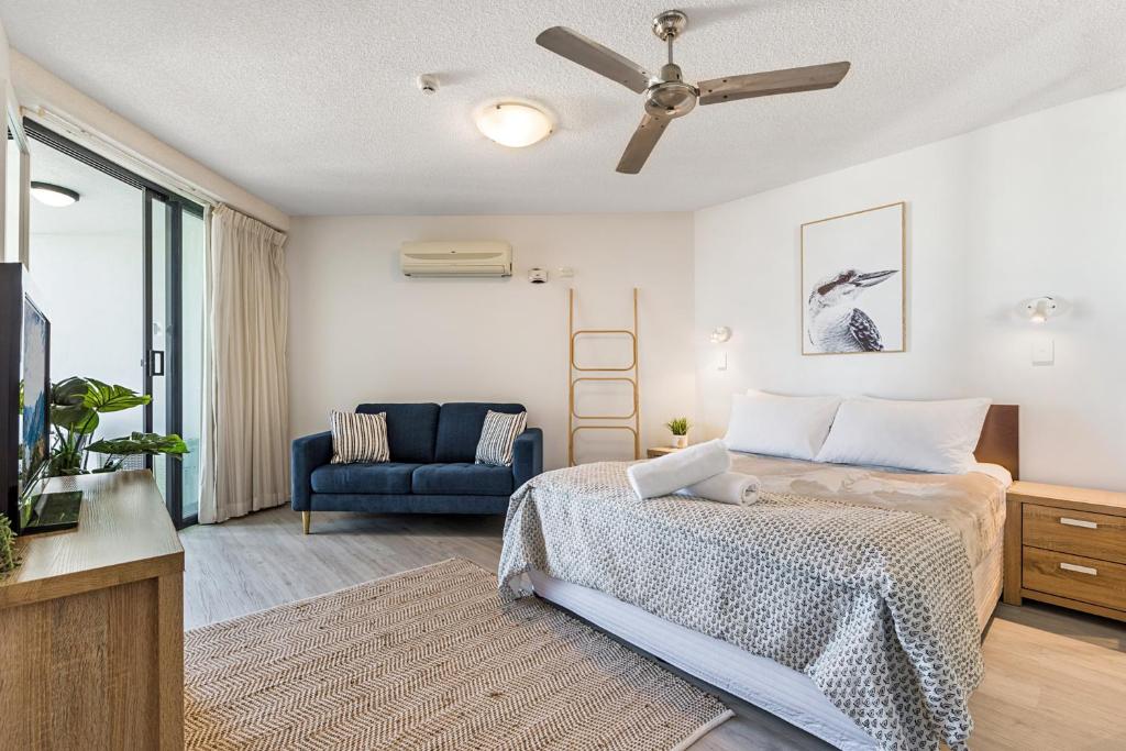 1 dormitorio con 1 cama y 1 sofá azul en Coolum Beachside Studio, en Coolum Beach