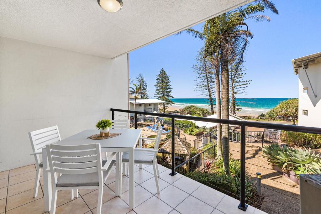 a balcony with a table and chairs and a view of the ocean at Coolum Beachside Apartment in Coolum Beach
