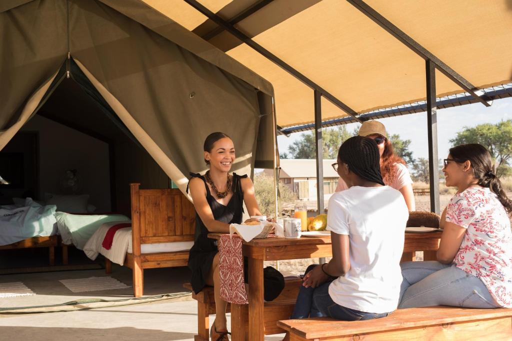 eine Gruppe von Menschen, die an einem Tisch in einem Zelt sitzen in der Unterkunft Namib Desert Camping2Go in Solitaire