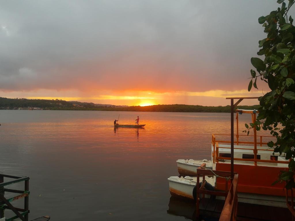 uma pessoa em um barco em um lago ao pôr do sol em Club Manguaba Beira Rio em Japaratinga