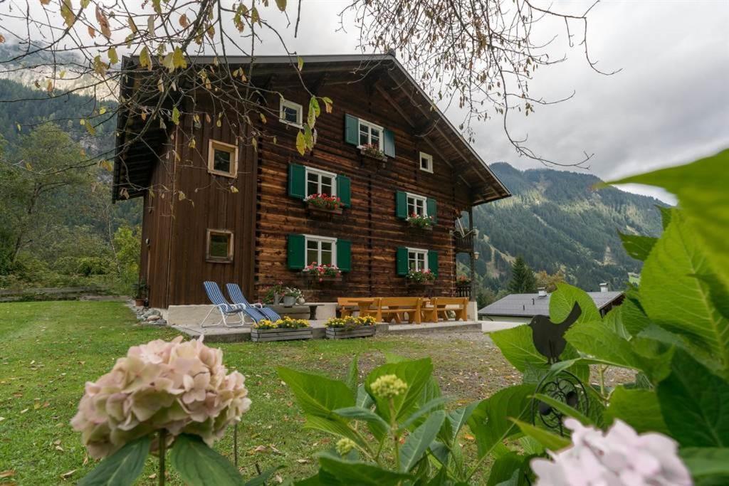 a wooden house with green shuttered windows and flowers at Ferienhaus Bergfrieden in Partenen