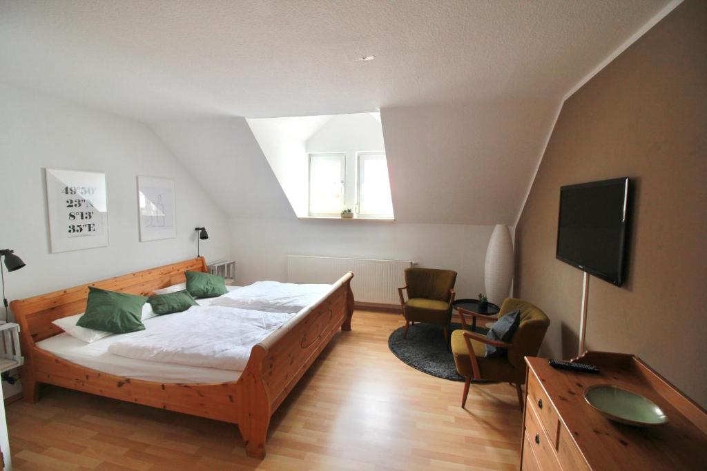 a bedroom with a bed with green pillows and a tv at das Eppelsheimer in Undenheim