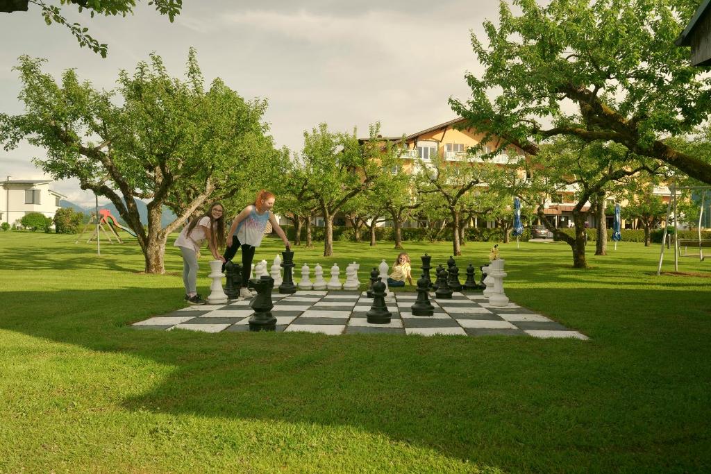 two people playing chess on a giant chessboard in a park at Hotel Pachernighof in Velden am Wörthersee