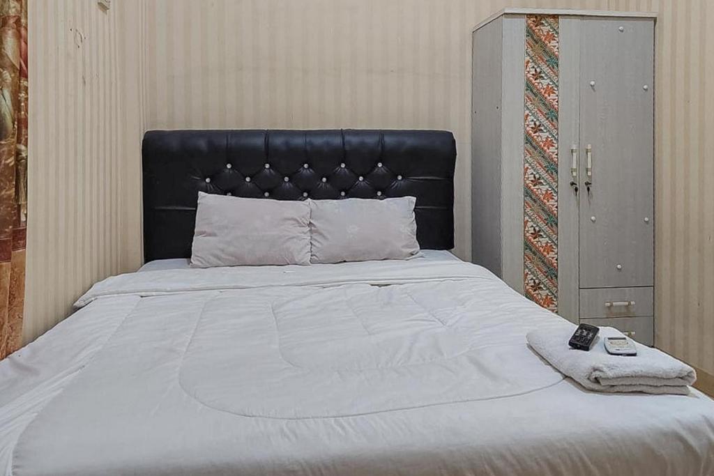 un lit avec tête de lit noire et télécommande dans l'établissement Icha Homestay near Terminal Purabaya Madiun, à Madiun