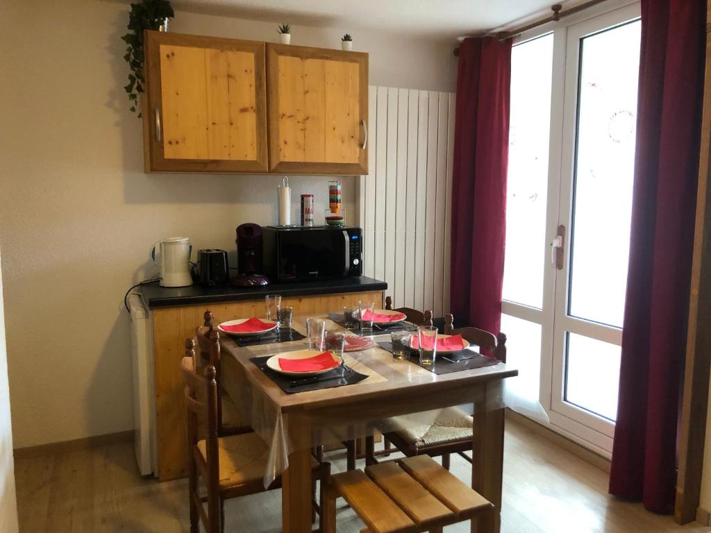 eine Küche mit einem Tisch mit Stühlen und einer Mikrowelle in der Unterkunft Petit appartement confort Les 2 Alpes résidence Arc en Ciel télésiège Petite Aiguille in Les Deux Alpes