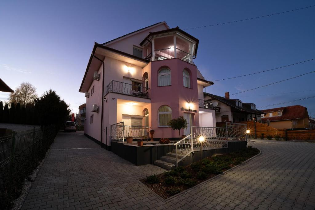 ein rosafarbenes Gebäude mit einem Uhrturm darüber in der Unterkunft Villa Lotus in Zalakaros
