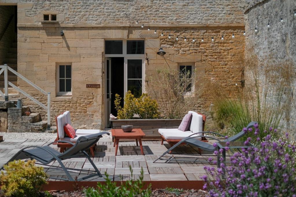 a patio with two chairs and a table at Le Domaine de l&#39;Hostellerie in Le Fresne-Camilly
