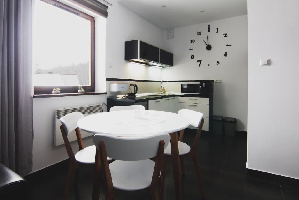 a kitchen with a table and chairs and a clock on the wall at Apartament Górski - SPA pod Nosalem in Zakopane