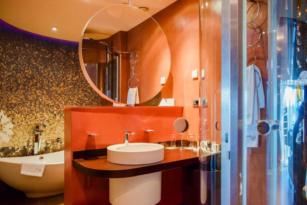 a bathroom with a sink and a mirror and a tub at Les Fleurs Boutique Hotel in Sofia