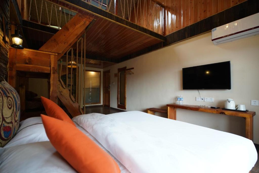 a bedroom with two beds and a flat screen tv at Floral Hotel Luguhu Chujian Xiaoyin in Zuosuo
