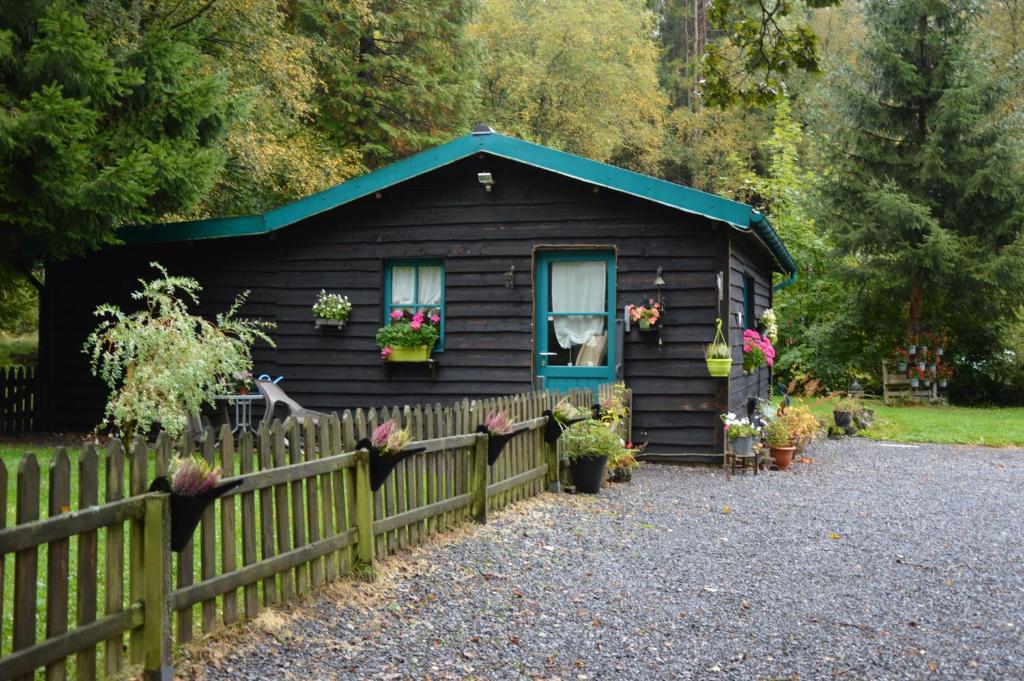 a black shed with flowers on the window and a fence at Le Chalet De Papitou in Hockai