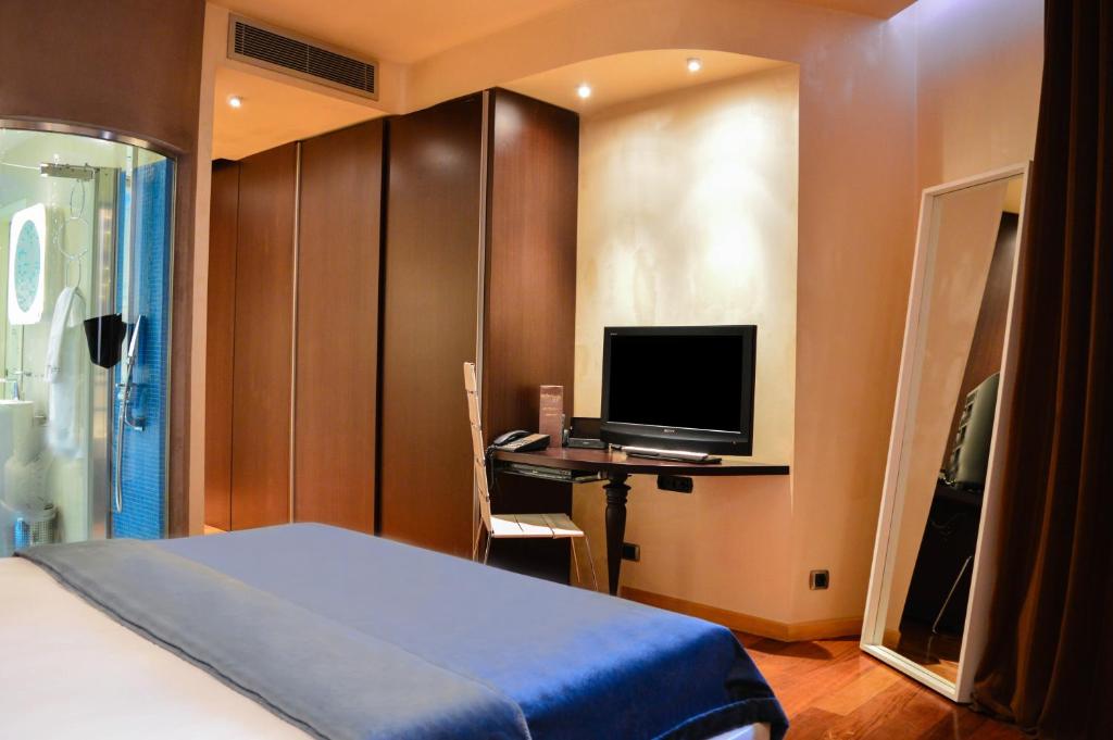 a bedroom with a bed and a desk with a television at Les Fleurs Boutique Hotel in Sofia