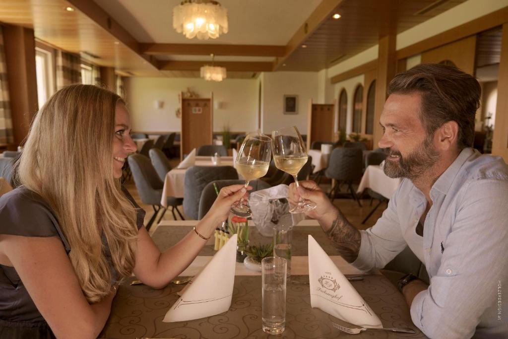 a man and woman sitting at a table drinking wine at Hotel Pachernighof in Velden am Wörthersee