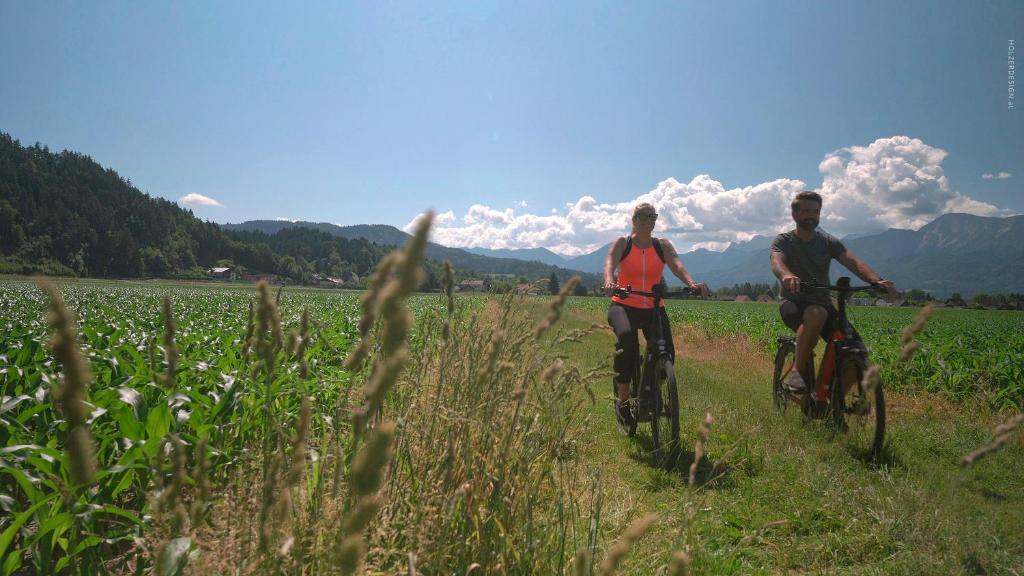 two people riding bikes in a field of grass at Hotel Pachernighof in Velden am Wörthersee