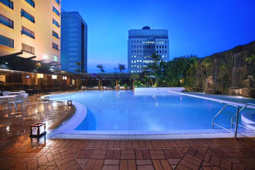 a large swimming pool in a city at night at Menara Peninsula Hotel in Jakarta