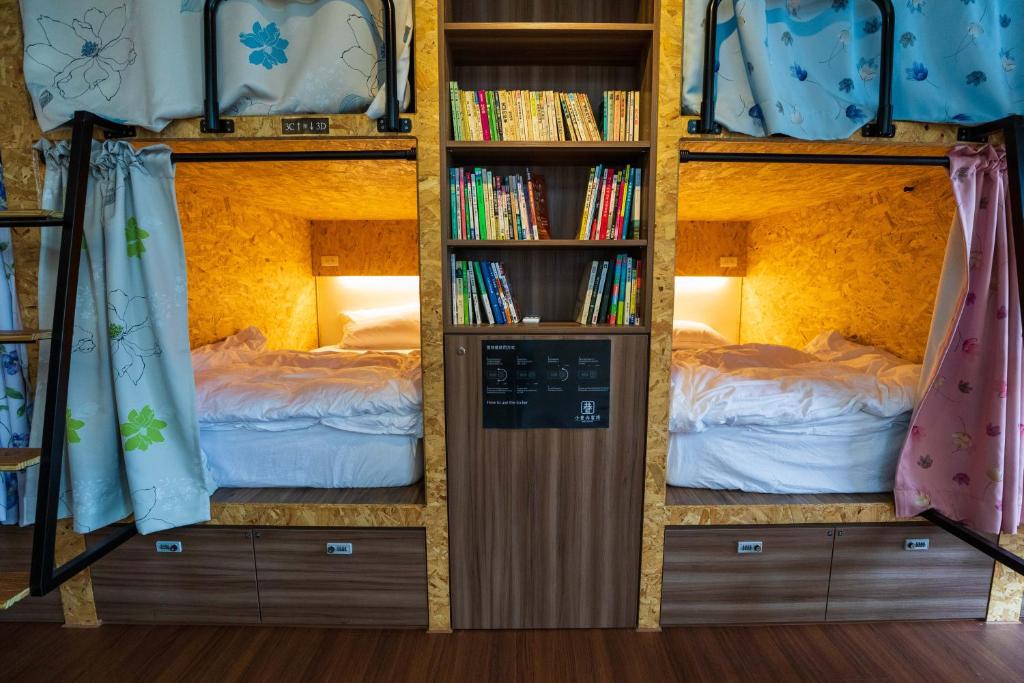 a room with three bunk beds with books at Hostel Alley Inn -桃園民宿075 in Daxi