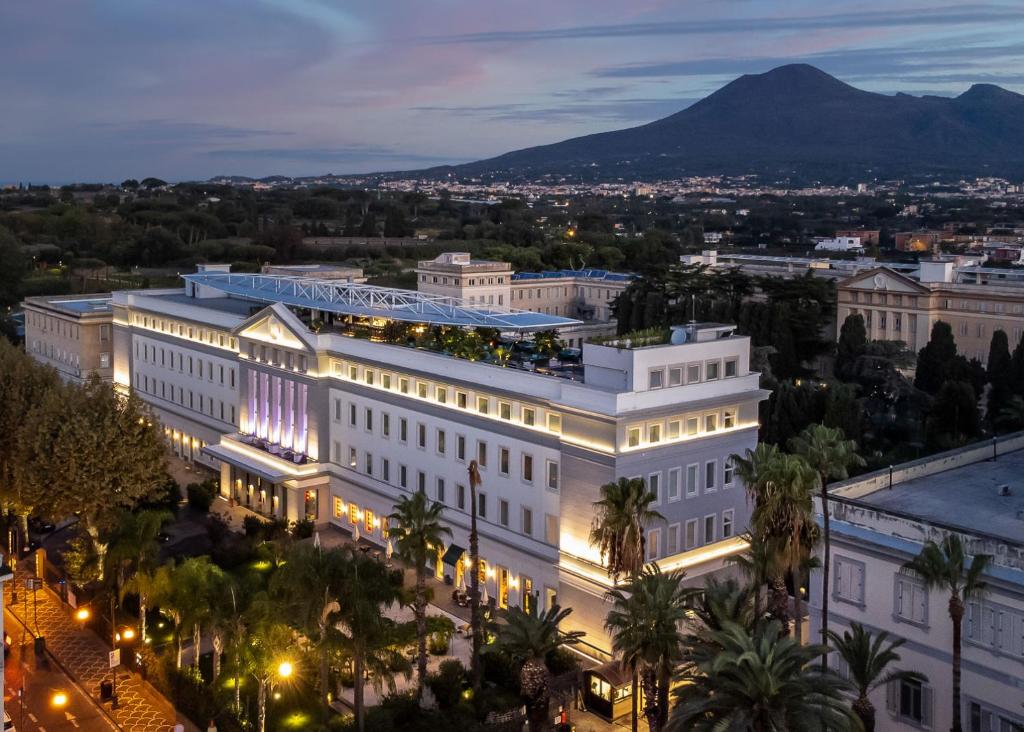 a large white building with a mountain in the background at Habita79 Pompeii - MGallery in Pompei