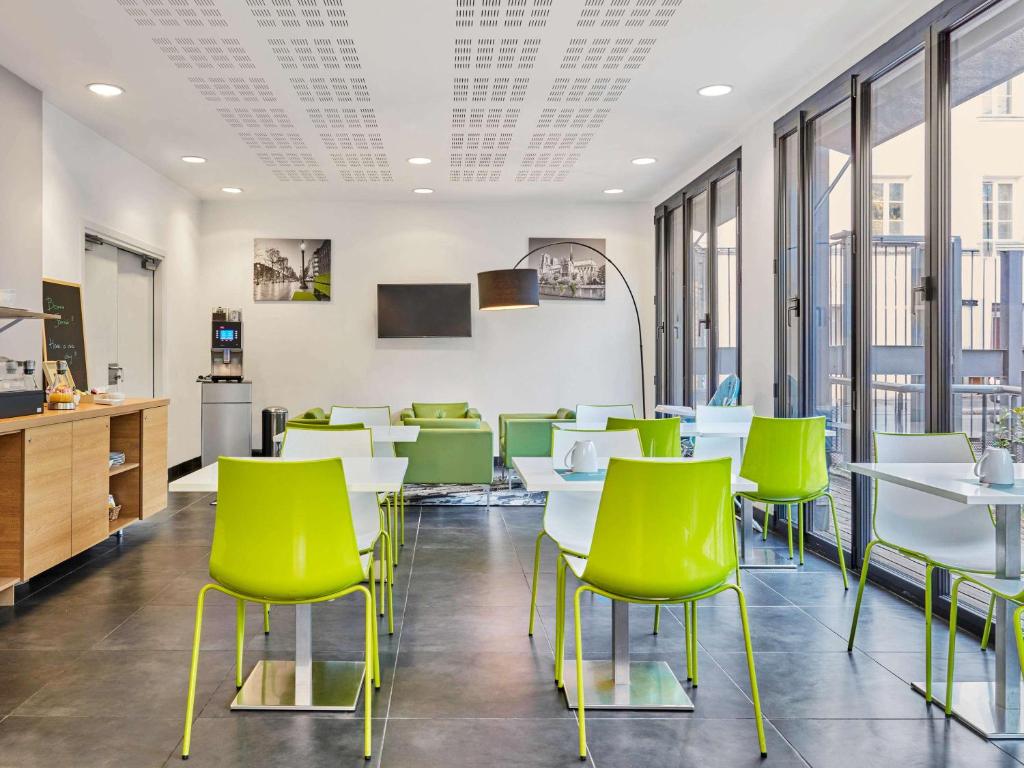 a cafeteria with white tables and green chairs at Aparthotel Adagio Access Paris Bastille in Paris