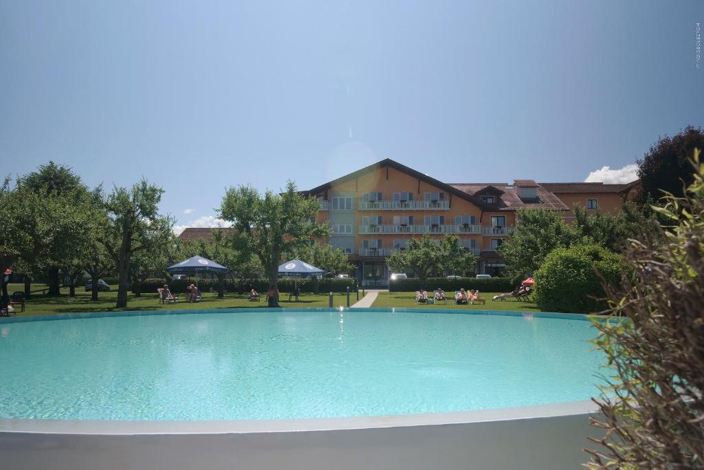a large swimming pool in front of a building at Hotel Pachernighof in Velden am Wörthersee