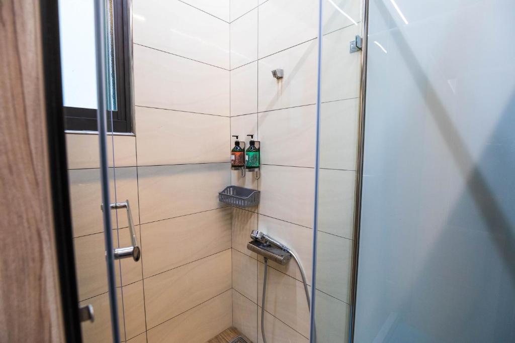 a shower with two bottles of alcohol on a shelf at Hostel Alley Inn -桃園民宿075 in Daxi