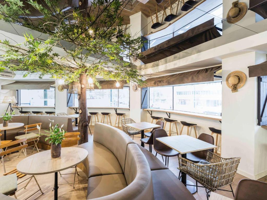 un restaurant avec des tables, des chaises et un arbre dans l'établissement Ibis Styles Lisboa Centro Marquês de Pombal, à Lisbonne