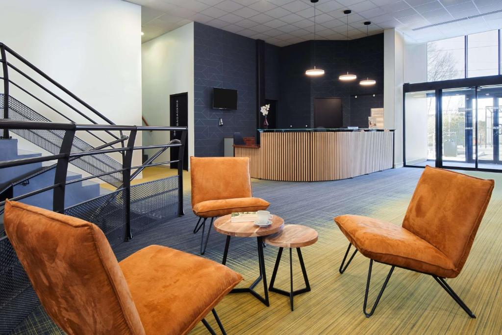 a lobby with chairs and a table and a staircase at Sure Hotel by Best Western Nantes Beaujoire in Nantes