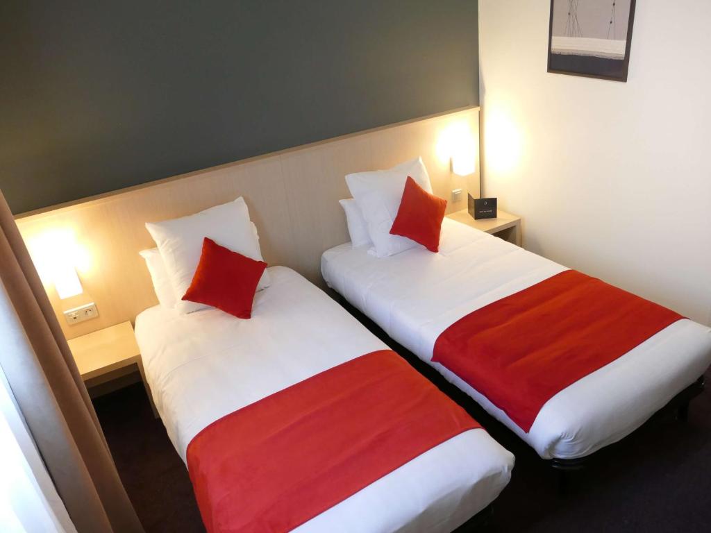 two beds in a hotel room with red and white sheets at Sure Hotel by Best Western Nantes Beaujoire in Nantes