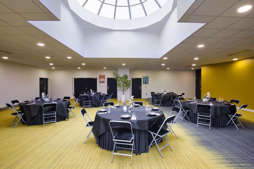a conference room with tables and chairs and a large ceiling at Sure Hotel by Best Western Nantes Beaujoire in Nantes