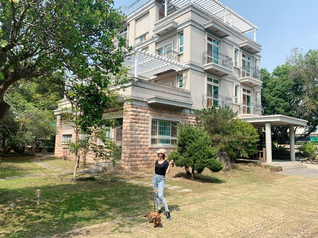 Una donna in piedi davanti a una casa con un cane di Shinchen 88 Villa a Dongshi
