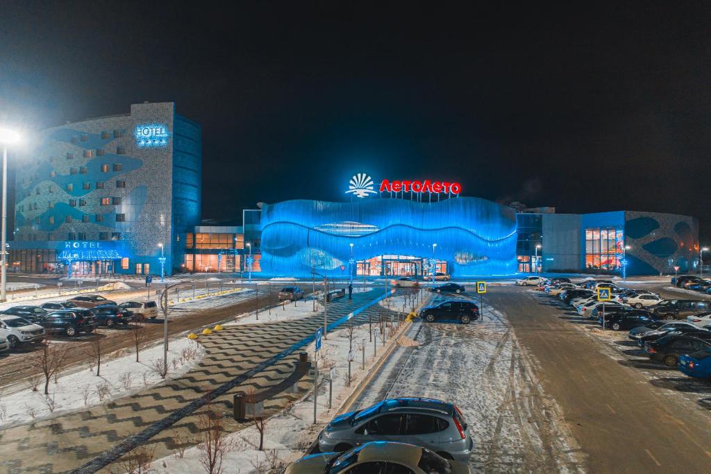 un gran edificio azul con coches estacionados en un estacionamiento en ЛетоЛето Термал Резорт & СПА, en Tyumen